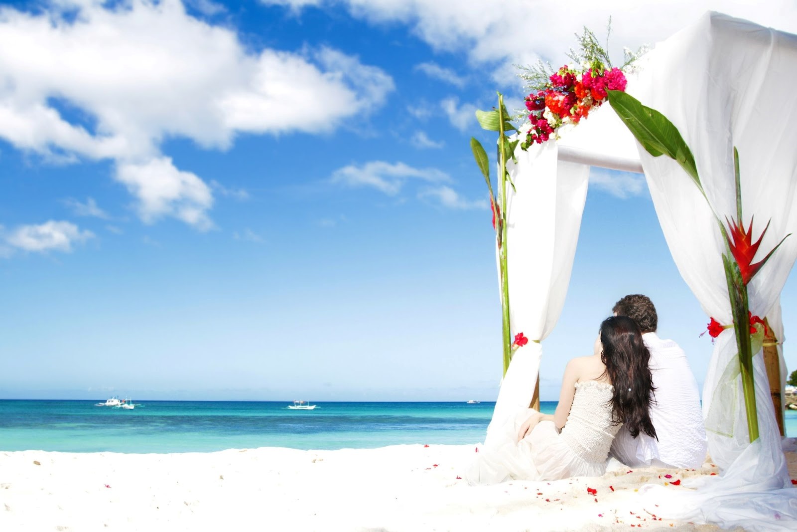 Couple under a floral wedding canopy on the beach